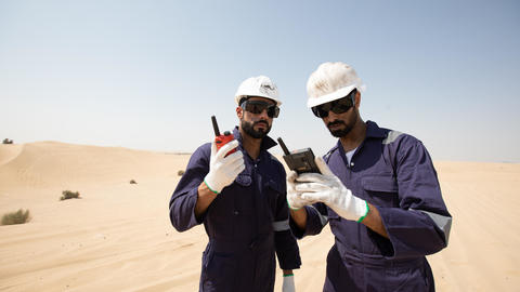 tactilon agnet and tetra - 2 business critical workers looking at their devices in the dessert
