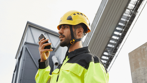 entreprises business critical industry user with a yellow helmet speaking to a smartphone 