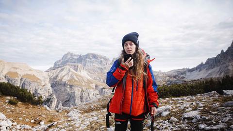 Hiker woman using Agnet over satcom with her smartphone in the mountains