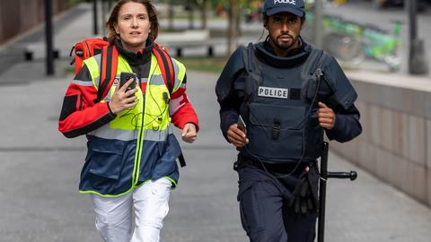 paramedic female and police male running for an emergency with their phones in hands