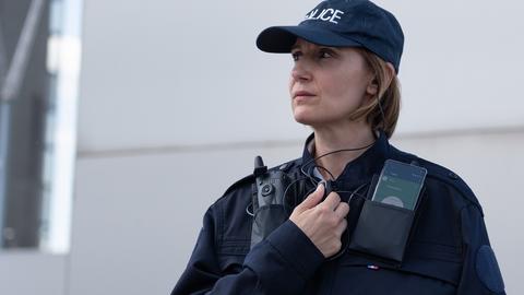 Police woman equipped with radio device and smartphone displaying Agnet using PTT accessory