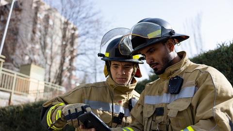two firemen looking at a ruggedized tablet one showing something on the screen