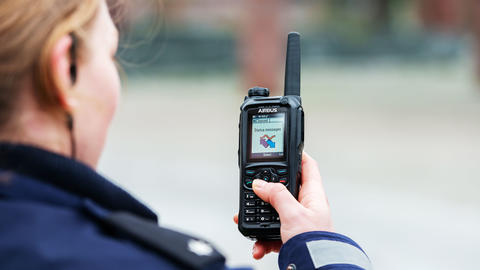 Police officer scrolling the menu of a TH9 TETRA terminal