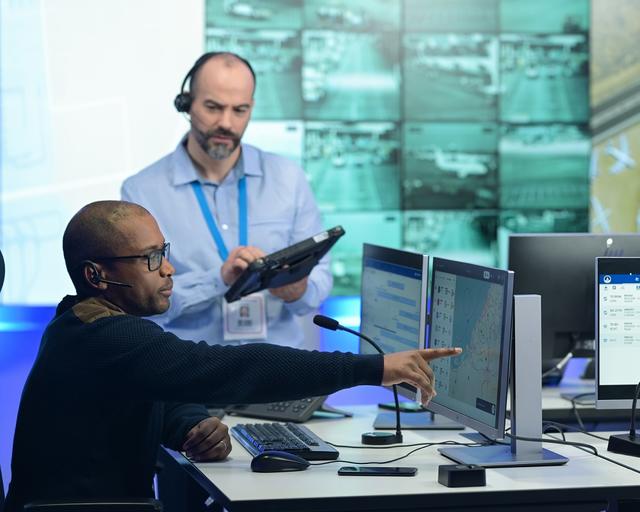 airport control room male dispatcher showing agnet turnaround on the screen to his male colleague with a woman colleague in the background.jpg