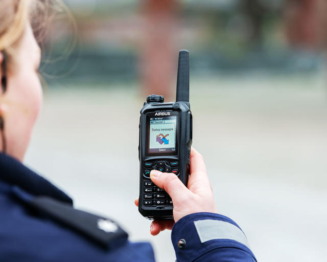 Police officer scrolling the menu of a TH9 TETRA terminal Police officer scrolling the menu of a TH9 TETRA terminal