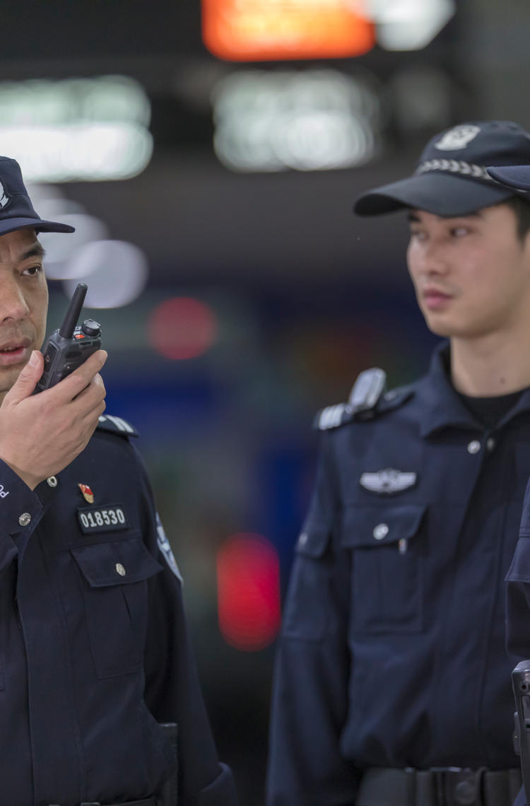 TETRA - Guangzhou police speaking to a device with other two standing next to him TETRA - Guangzhou police speaking to a device with other two standing next to him