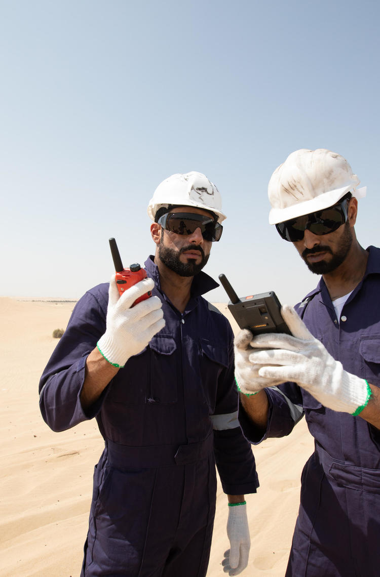 tactilon agnet and tetra - 2 business critical workers looking at their devices in the dessert tactilon agnet and tetra - 2 business critical workers looking at their devices in the dessert