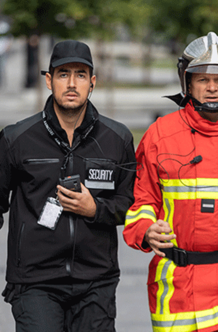 security and fireman running in the street phone in their hand security and fireman running in the street phone in their hand