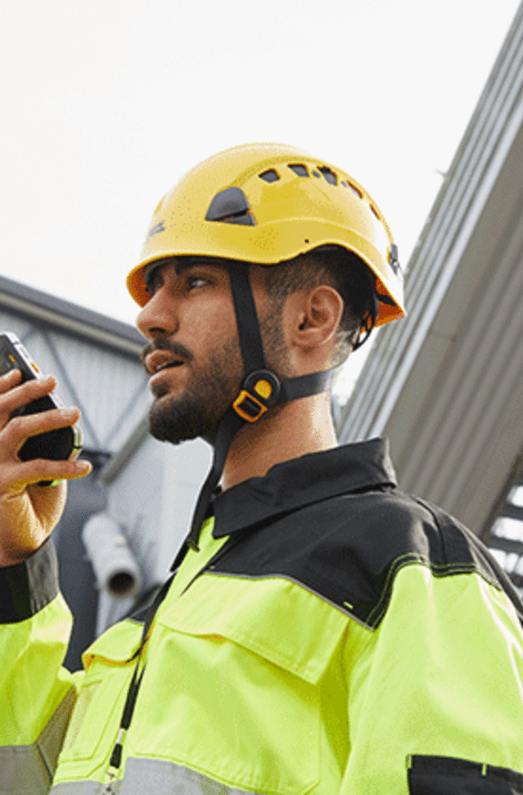 entreprises business critical industry user with a yellow helmet speaking to a smartphone  entreprises business critical industry user with a yellow helmet speaking to a smartphone