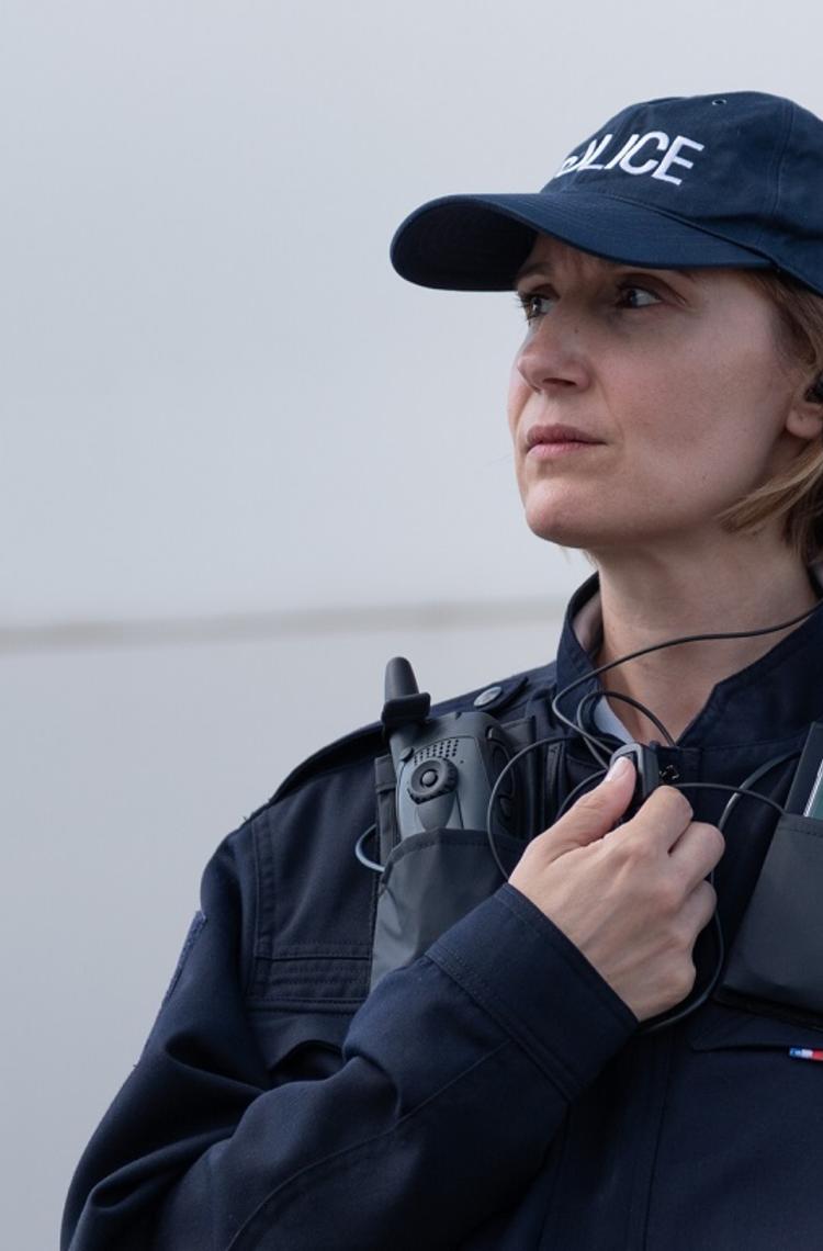 Police woman equipped with radio device and smartphone displaying Agnet using PTT accessory Police woman equipped with radio device and smartphone displaying Agnet using PTT accessory