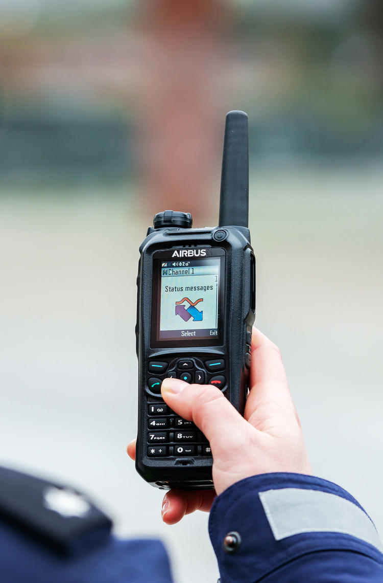 Police officer scrolling the menu of a TH9 TETRA terminal