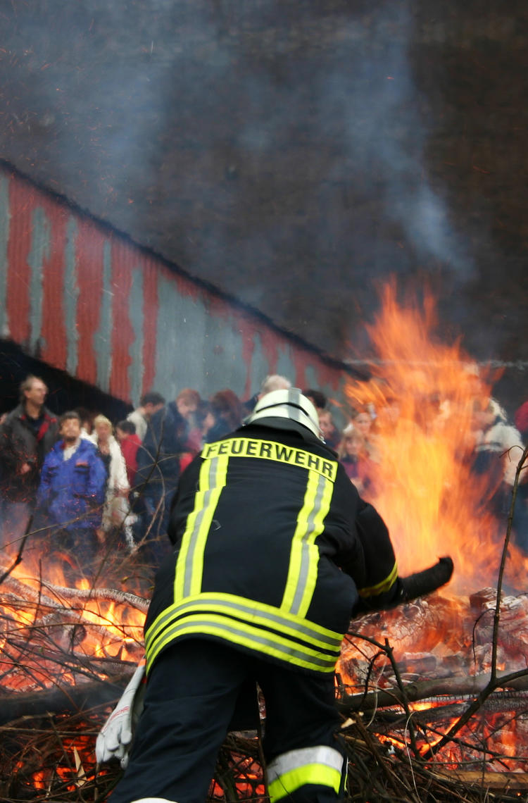 Firefighter fighting flames with crowd watching Firefighter fighting flames with crowd watching
