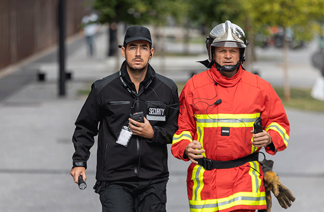 security and fireman running in the street phone in their hand