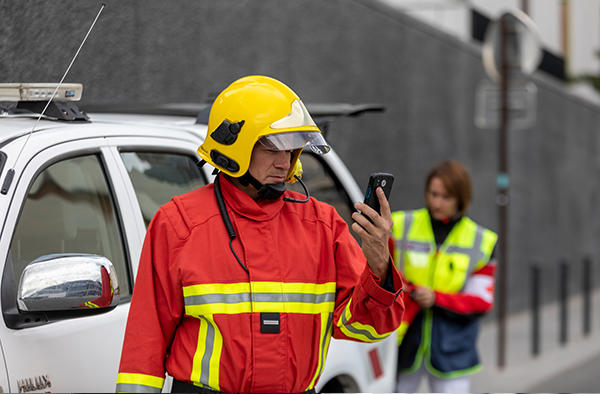 push to talk - fireman using a smartphone white car and a medic in the background