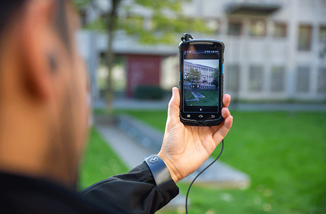 push to talk with video - guy using a phone to film a building from outside