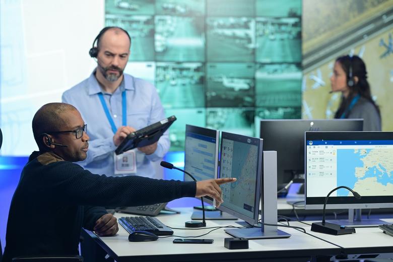 airport control room male dispatcher showing agnet turnaround on the screen to his male colleague with a woman colleague in the background.jpg