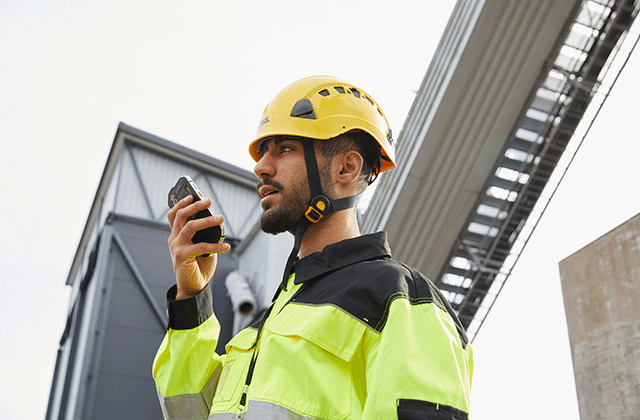 entreprises business critical industry user with a yellow helmet speaking to a smartphone