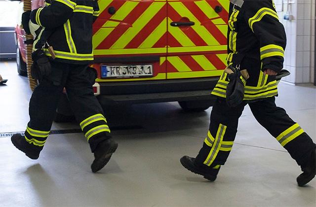 close bottom view on two firefighters running into a fire truck in the fire station