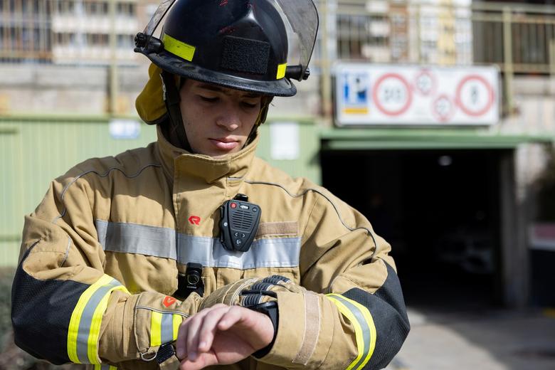 Fireman equiped with PPT accessory and body cam looking at his smart watch