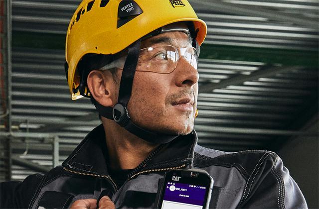 Industry worker uses external PTT with smartphone and Agnet