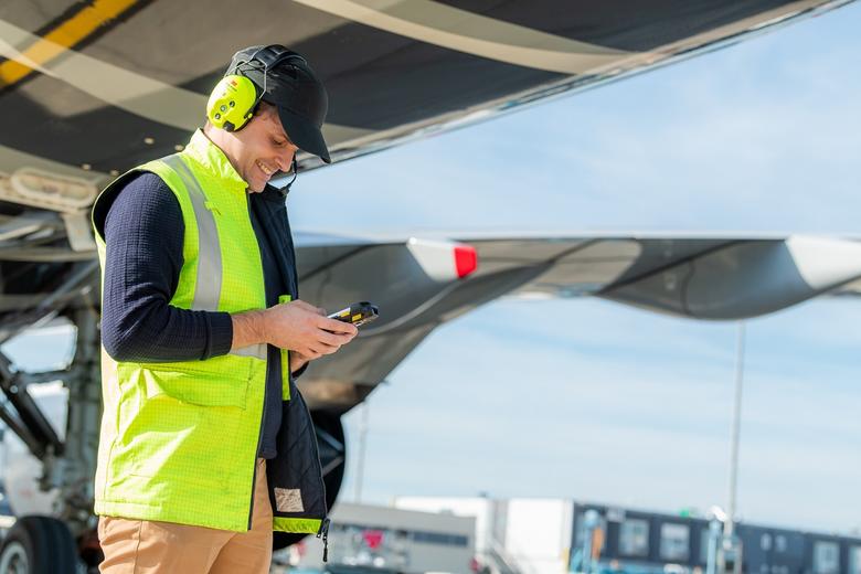 Maintenance guy on the tarmac using his ruggedized smartphone for an aircraft turnaround