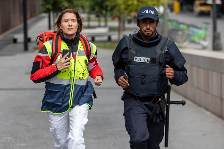 paramedic female and police male running for an emergency with their phones in hands