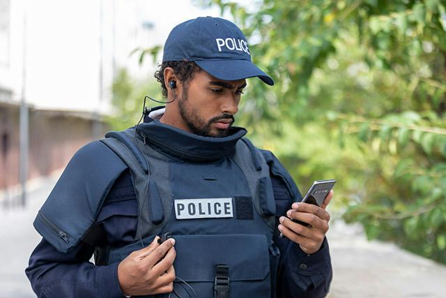 Police officer looks at his smartphone