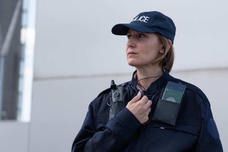 Police woman equipped with radio device and smartphone displaying Agnet using PTT accessory