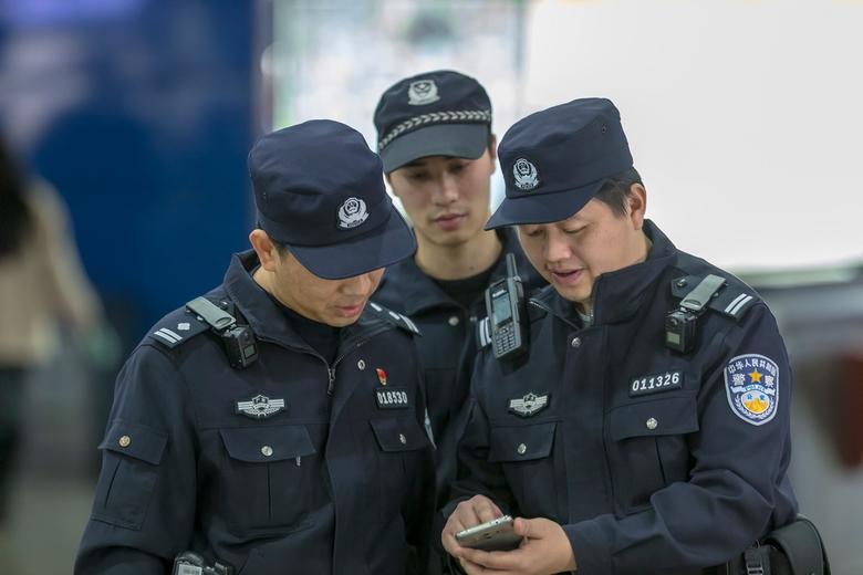 Three Guangzhou police men looking at a smartphone