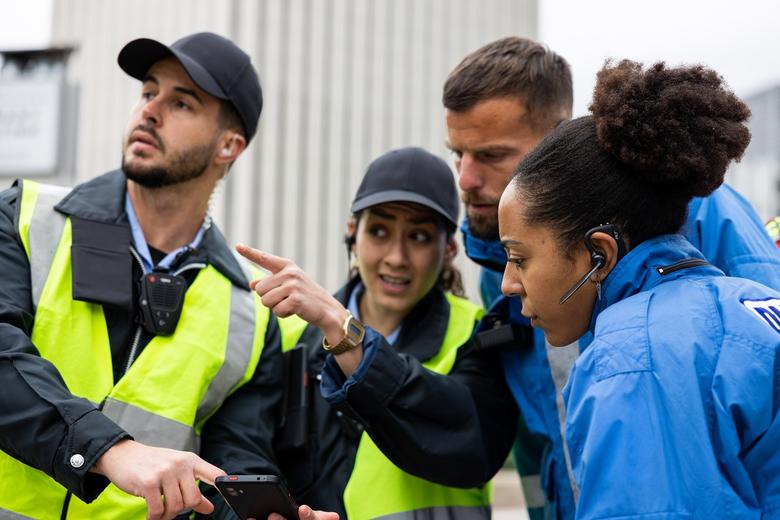 two police officers working with two paramedics during an emergency police female showing something offscreen
