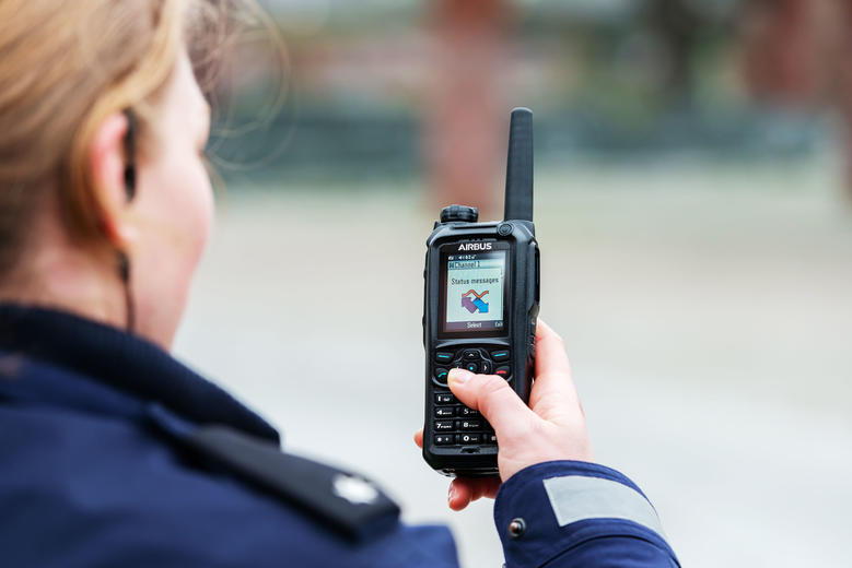 Police officer scrolling the menu of a TH9 TETRA terminal